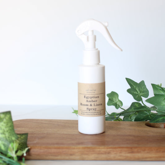 White spray bottle with a brown label on a white background with green plants.